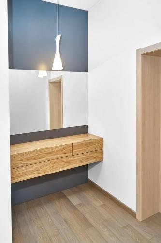 Floating cabinet of natural timber under large mirror in room